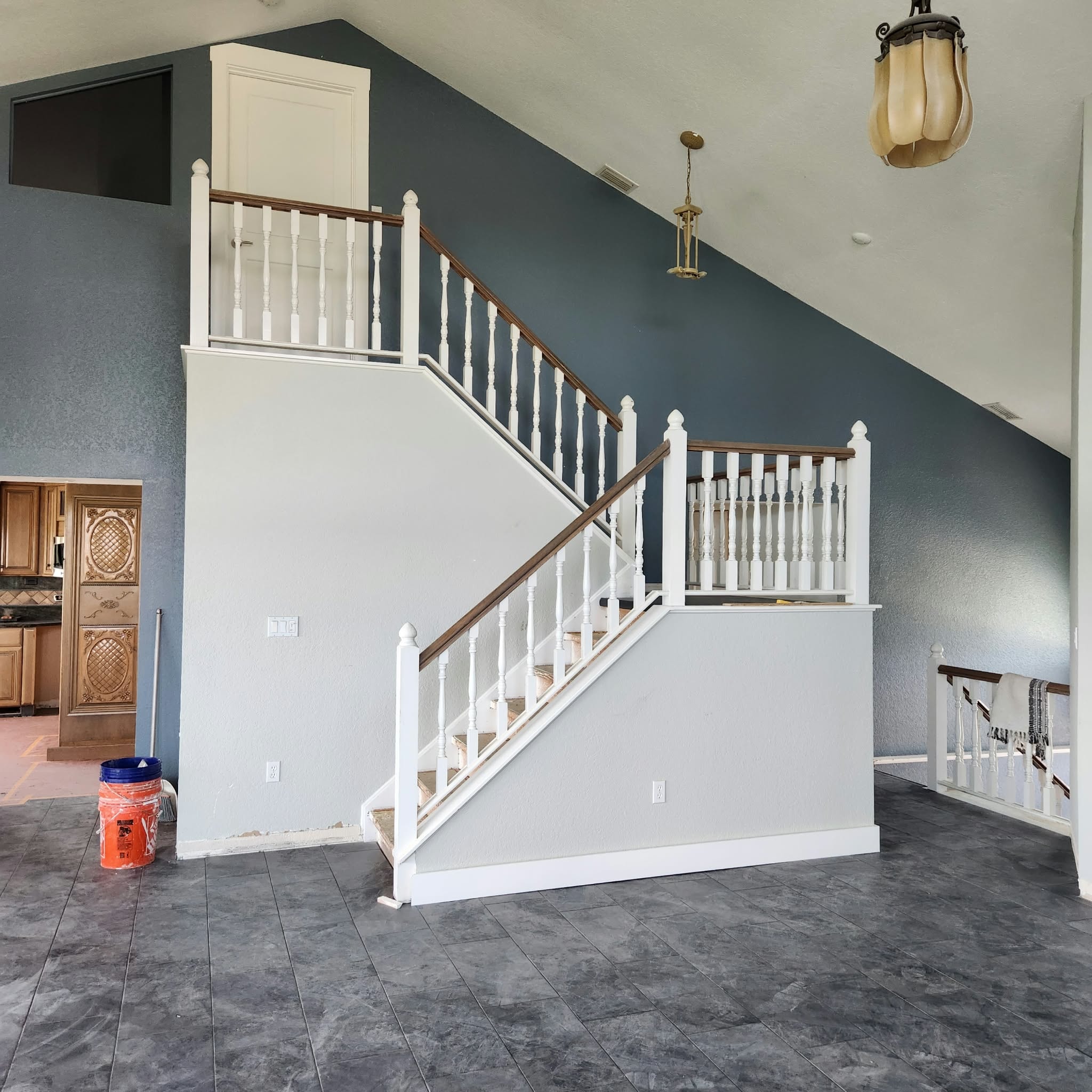 Renovated staircase with white balusters, wood handrail and slate-blue accent wall