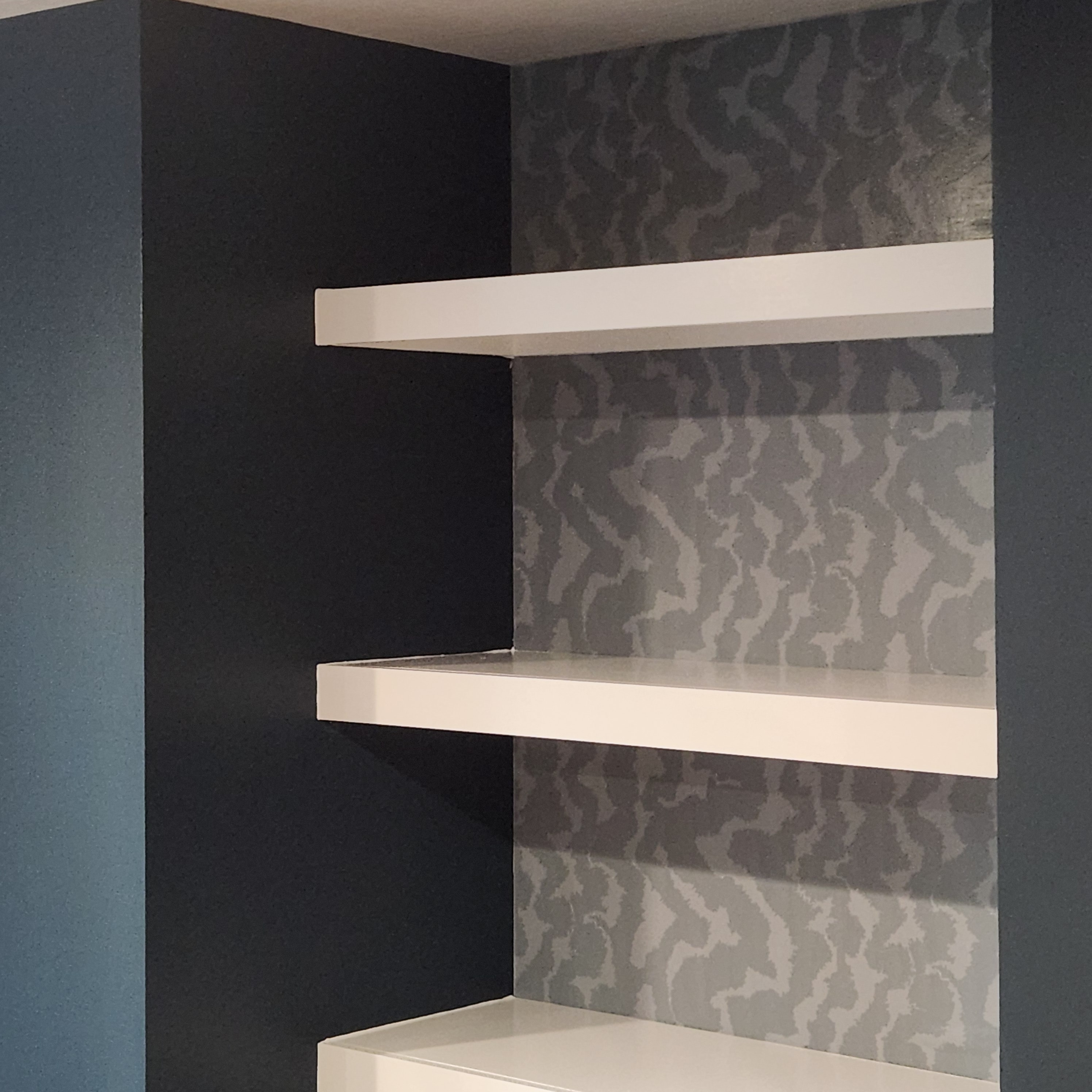 White floating shelves on navy wall by Devine N Counters