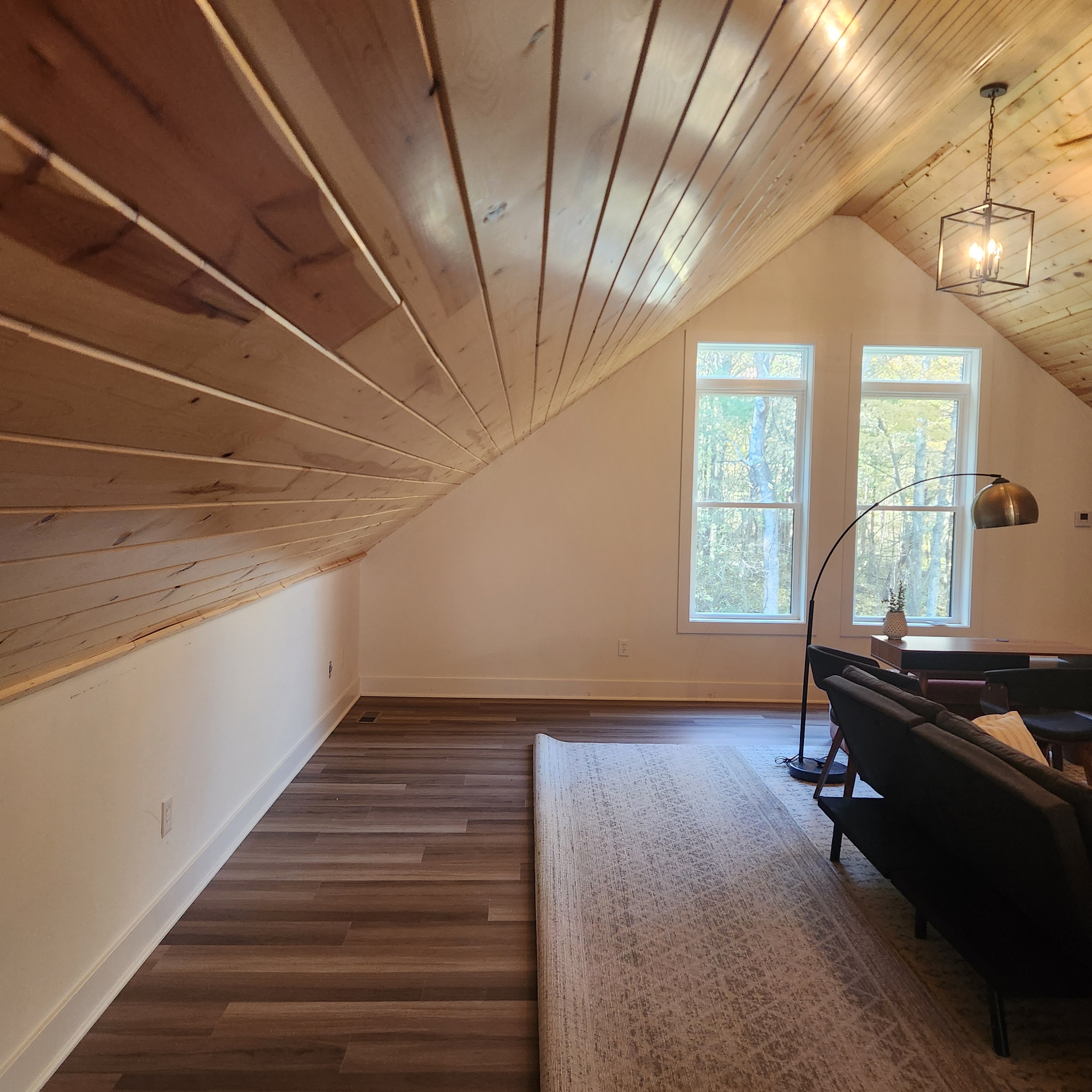 Great room with vaulted pine ceiling, wood plank walls and new flooring